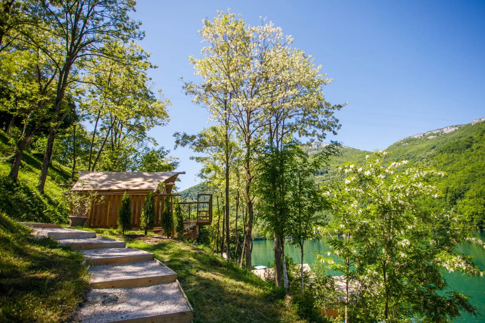 Glamping tent along a woodland path overlooking a lake